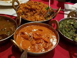 Indian curry platter featuring lamb curry, butter chicken, saag paneer and basmati rice
